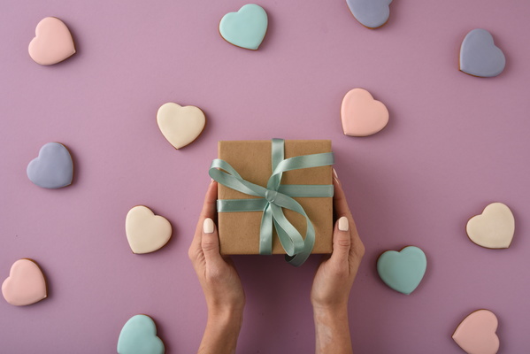 Girl Holing Present on Gift on Background of Heart-Shaped Cookies